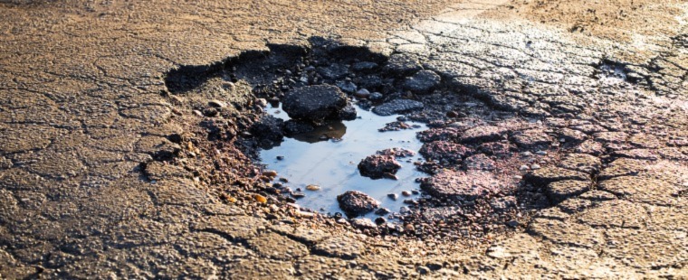 A pothole that cause damage to vehicles.